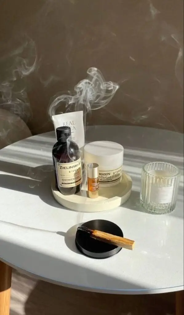 Aromatic skincare products with incense stick on table, sunlight casting shadows, serene atmosphere.