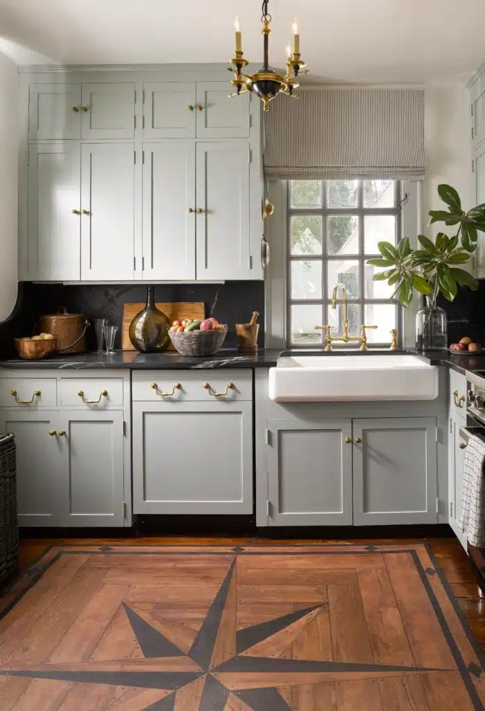 Elegant kitchen with farmhouse sink, white cabinets, wood floor, and black countertop accents.