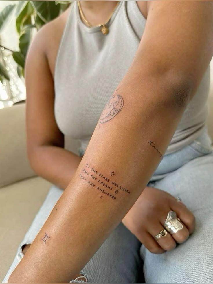 2369332d5d6032dd56cdb677e7df90ff Arm with delicate tattoos, including a quote and small symbols, showcasing minimalist ink designs against a casual outfit. | Sky Rye Design Arm with delicate tattoos, including a quote and small symbols, showcasing minimalist ink designs against a casual outfit.