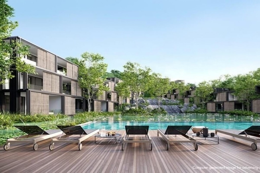 Modern luxury resort with wooden deck, loungers, pool, and lush greenery, under a clear blue sky.