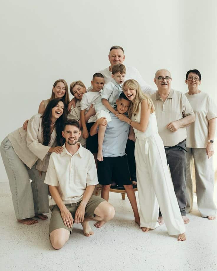 Happy family group photo in casual attire, posing together indoors with smiles and laughter.