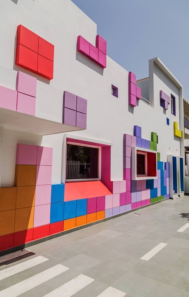 Colorful building exterior with geometric wall designs resembling Tetris blocks in vibrant pink, blue, and orange hues.