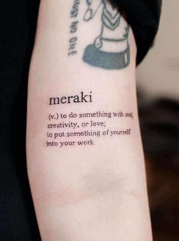 Tattoo of Meraki definition on arm, symbolizing creativity and love in one's work.