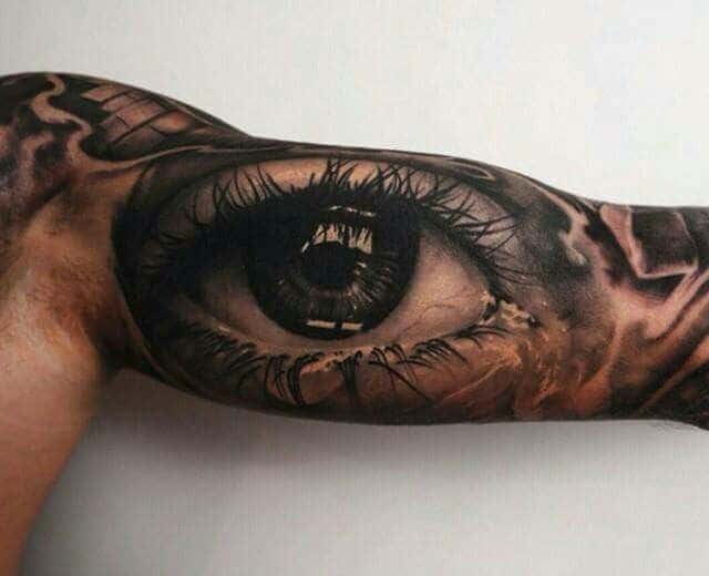 Realistic eye tattoo art on arm with intricate details and shading.