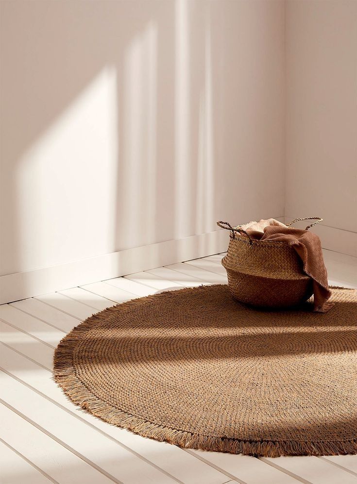 Round jute rug and woven basket in sunlit minimalist room, enhancing natural decor.