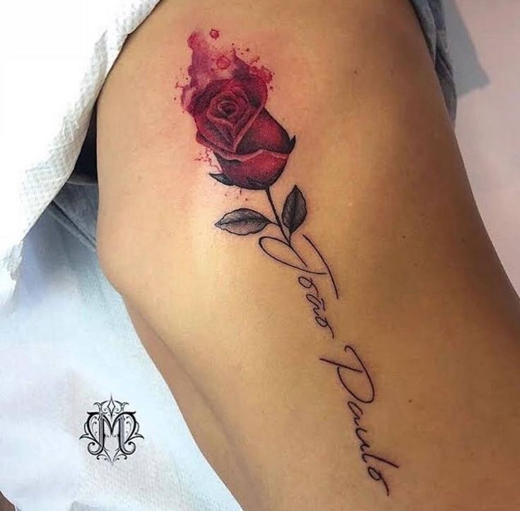 Red rose tattoo with script on inner arm, featuring elegant shading and personalized text.