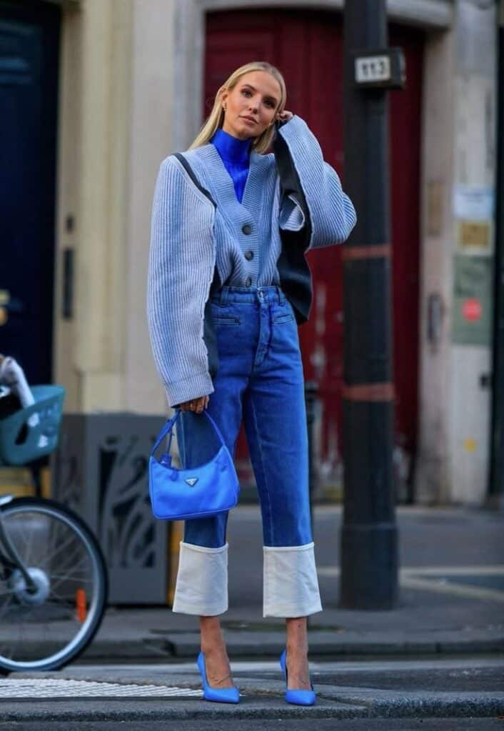 Stylish woman in blue outfit with matching bag and heels, posing confidently on a city street.