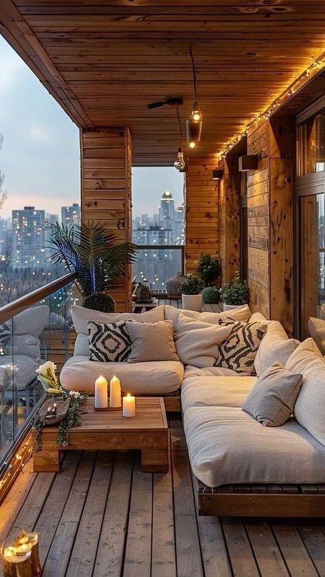 Cozy wooden balcony with comfy seating, candles, and nighttime city view for relaxing evenings.