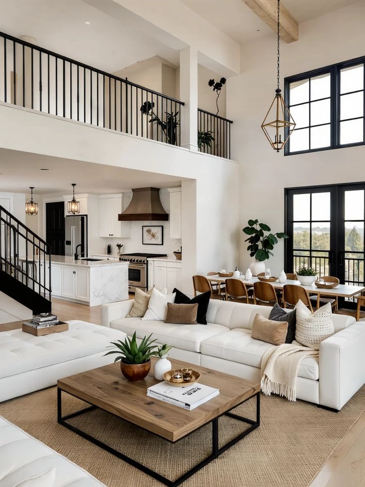 Modern open-concept living room with elegant decor, white sofa, wooden table, black windows, and kitchen in background.