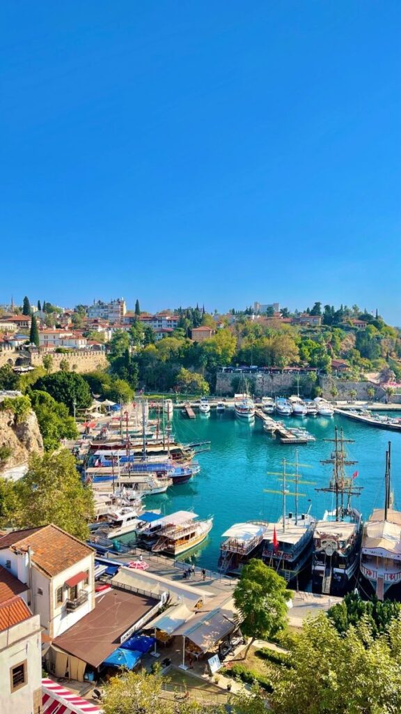 Scenic harbor view with boats and vibrant coastal town under a clear blue sky.