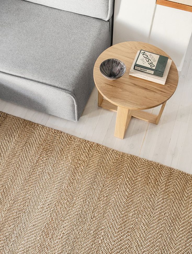 Modern living room with gray sofa, round wooden coffee table, and woven jute rug.