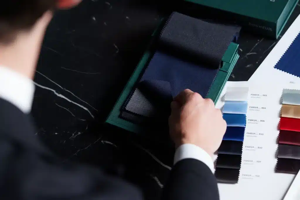 Person examining fabric samples in various colors on a dark table, showcasing textile variety.
