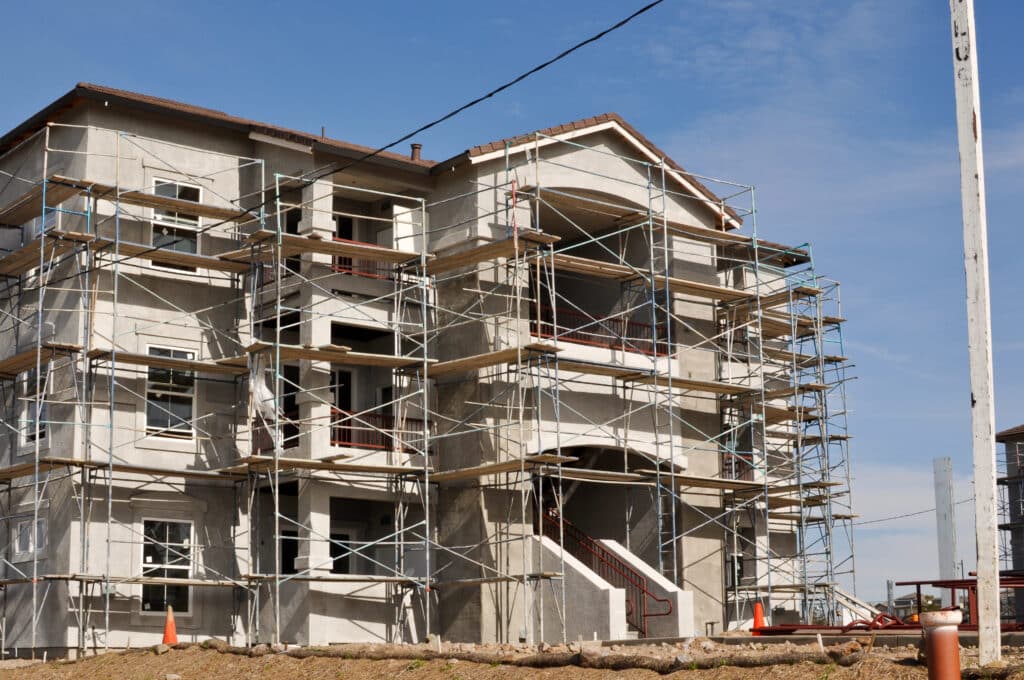 Depositphotos_10029591_XL Apartment building under construction with scaffolding and clear blue sky. | Sky Rye Design Apartment building under construction with scaffolding and clear blue sky.