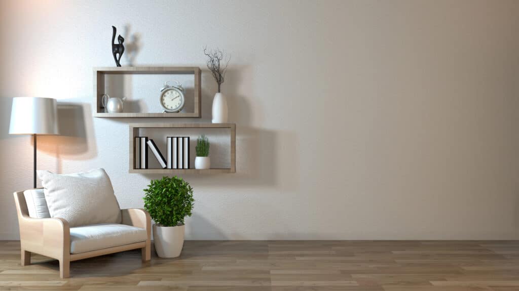 Minimalist living room with armchair, potted plant, and modern wall shelves featuring decor and books.