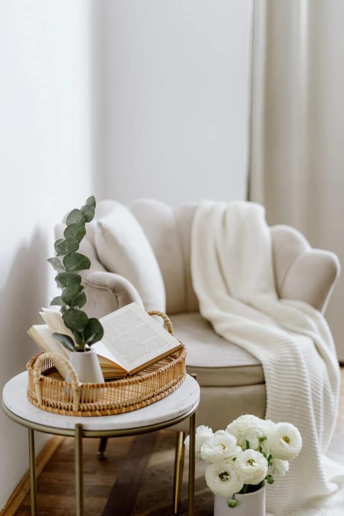 Depositphotos_593605626_XL Cozy reading nook with an armchair, blanket, open book, and flowers on a side table. Relaxing home decor scene. | Sky Rye Design Cozy reading nook with an armchair, blanket, open book, and flowers on a side table. Relaxing home decor scene.