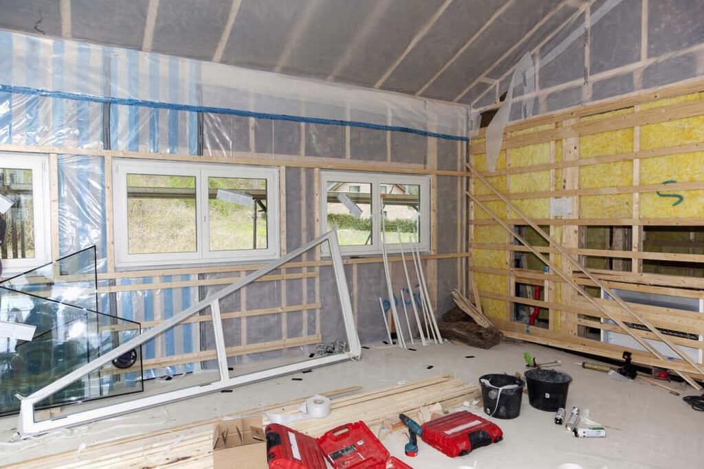 Home renovation in progress with new window installation and construction tools inside a partially insulated room.