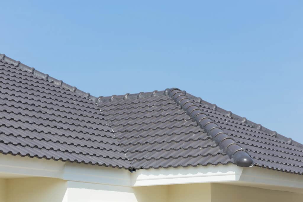 Modern gray tiled roof against a clear blue sky, showcasing durable and stylish roofing design.