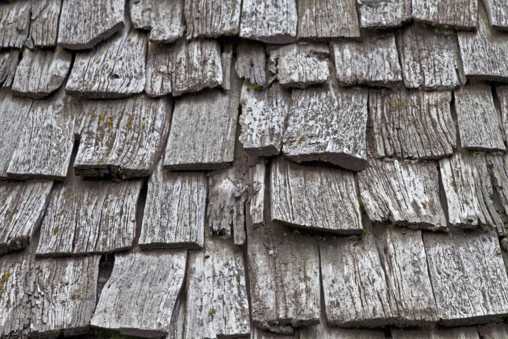 Close-up of weathered wooden shingles with visible texture and aging, showcasing rustic charm and natural wear.