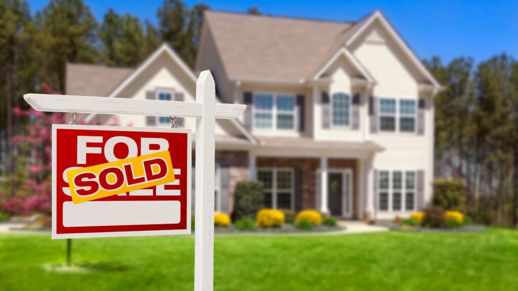 House with sold sign in front yard, symbolizing successful property sale in suburban neighborhood.