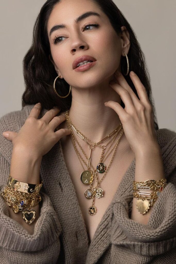 Woman wearing gold layered necklaces and bracelets, showcasing trendy jewelry fashion.