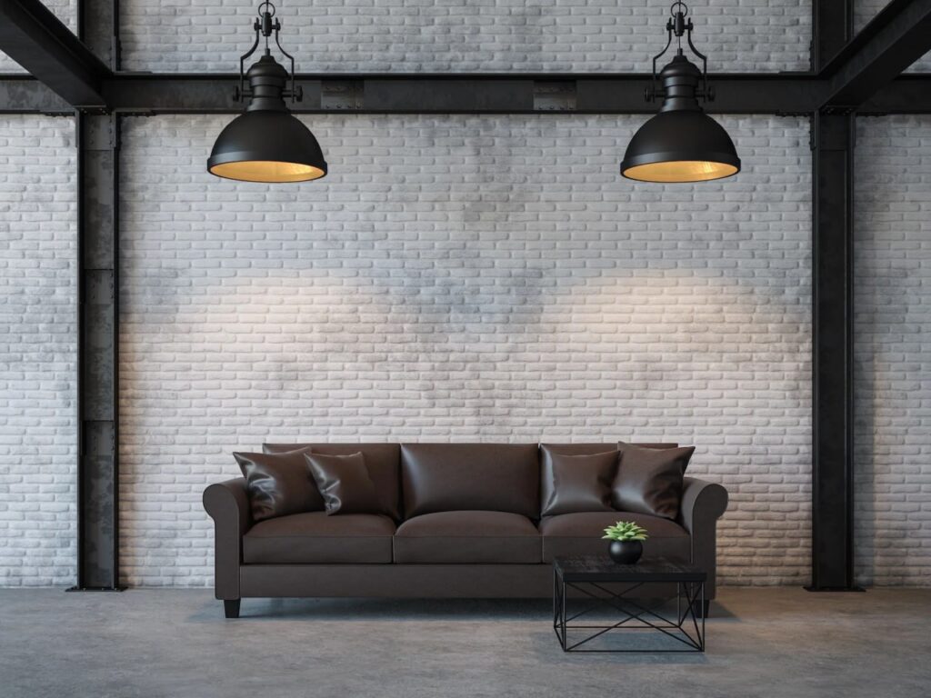 Industrial-style living room with black leather sofa, white brick wall, pendant lights, and metal-frame coffee table.