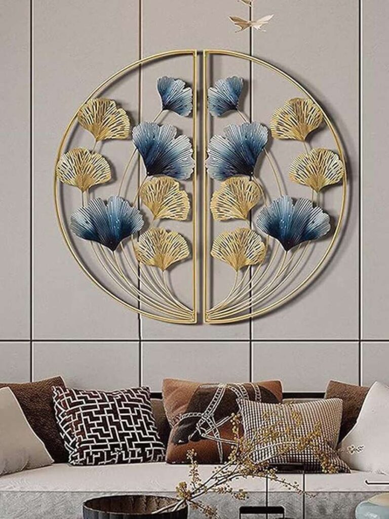 Modern living room with decorative metal wall art featuring blue and gold leaves above a stylish sofa with cushions.