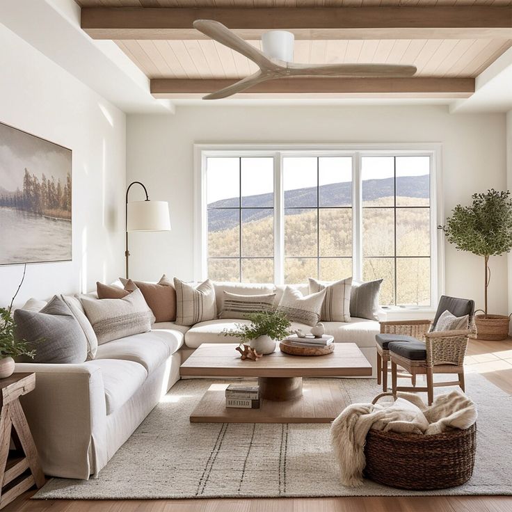 Modern living room with cozy beige sofa, wooden coffee table, large windows, and mountain view.