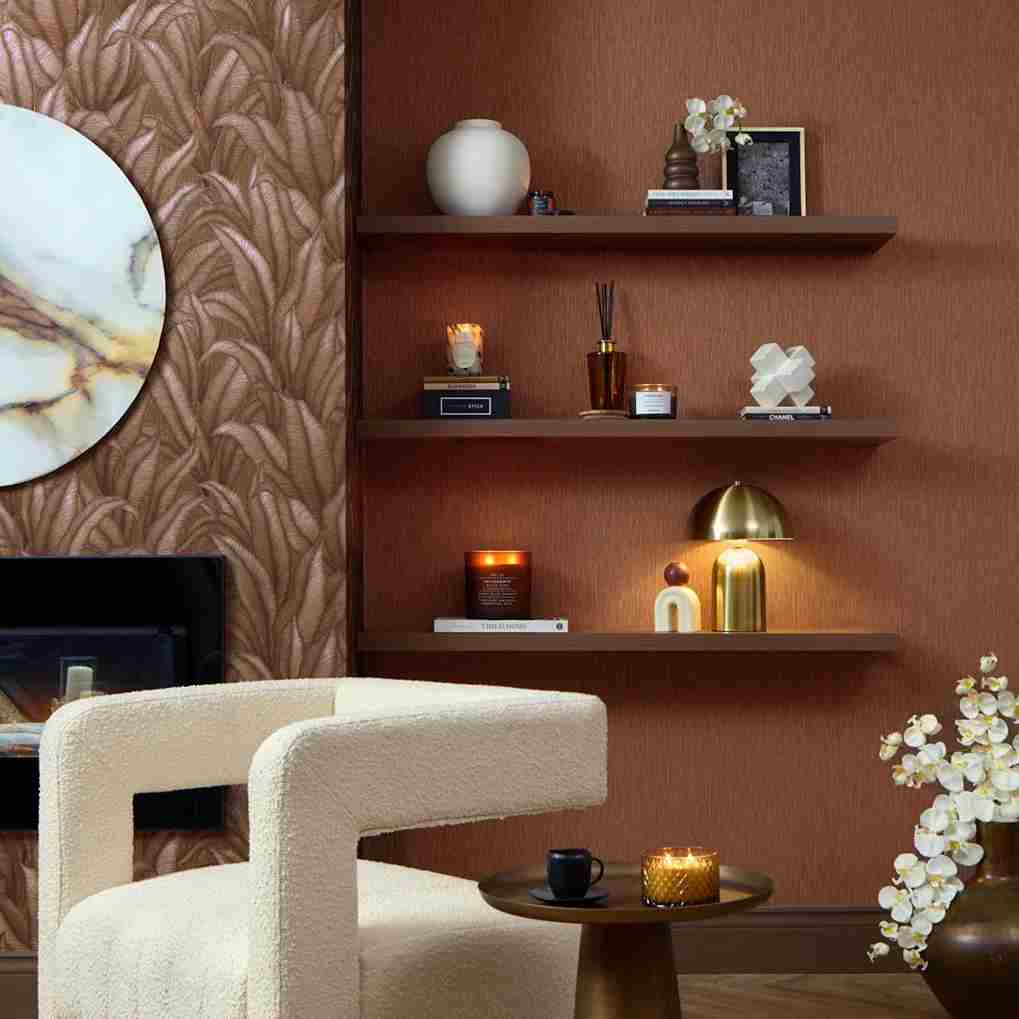 Modern living room with textured wallpaper, floating shelves, decorative items, and plush chair in warm tones.