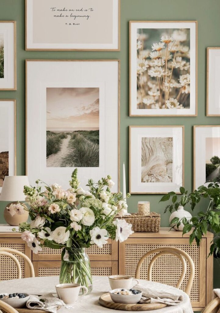 Cozy dining area with floral arrangement and framed wall art on green background. Rustic decor and soft lighting.
