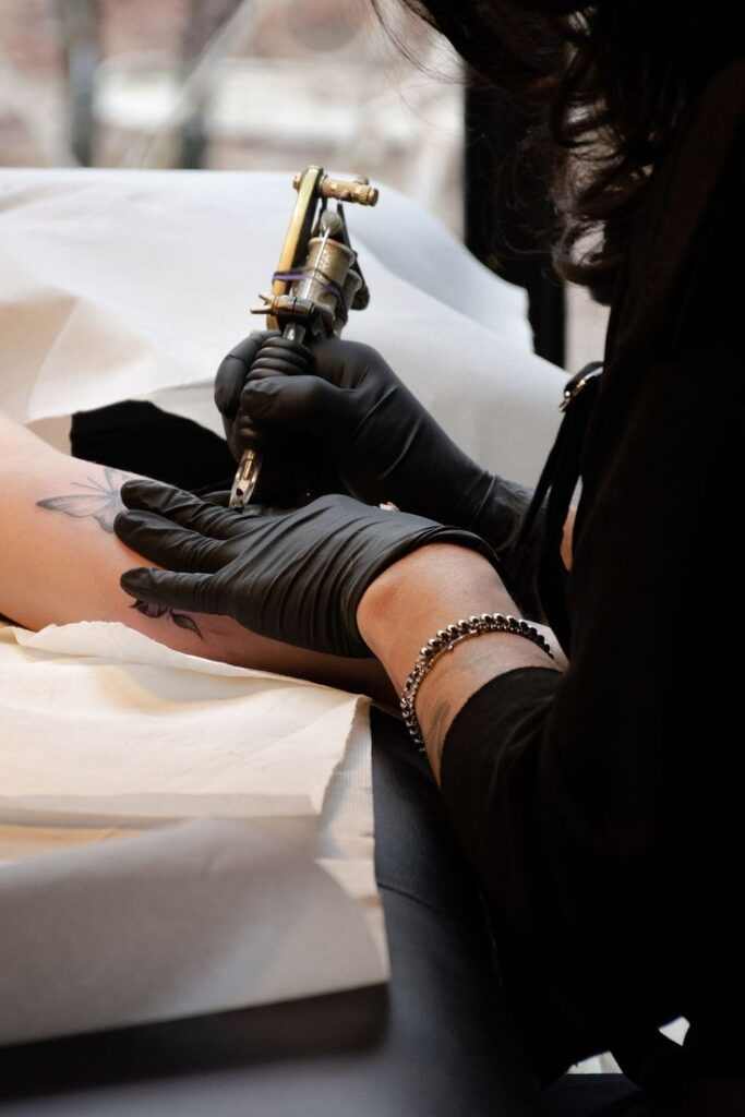 Spectacular Soaring bird tattoos that are surprisingly affordable_ Tattoo artist in gloves creating a butterfly tattoo on a client's arm in a studio setting. | Sky Rye Design Tattoo artist in gloves creating a butterfly tattoo on a client's arm in a studio setting.
