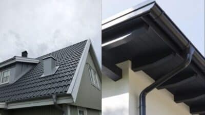 Gray metal roofing with matching gutters and eaves on a modern house against a cloudy sky.