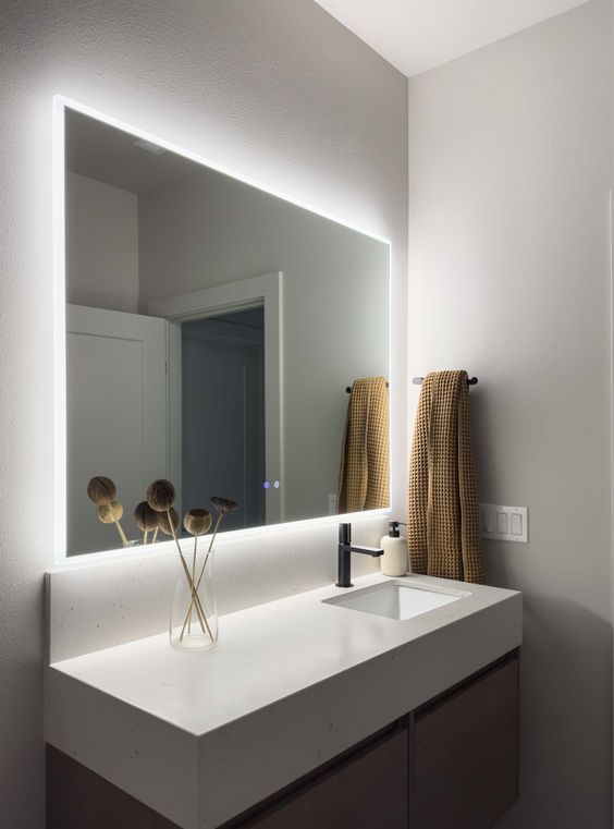 Modern bathroom vanity with illuminated mirror, minimalist decor, and dark wood cabinets. Elegant and sleek bathroom design.