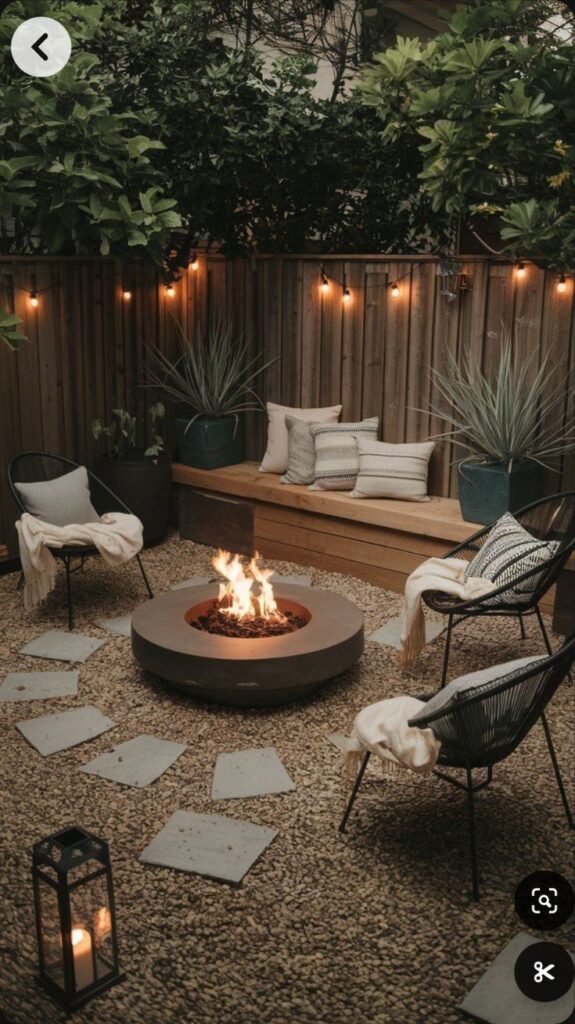 Cozy backyard with fire pit, string lights, chairs, and plants creating a warm outdoor ambiance.