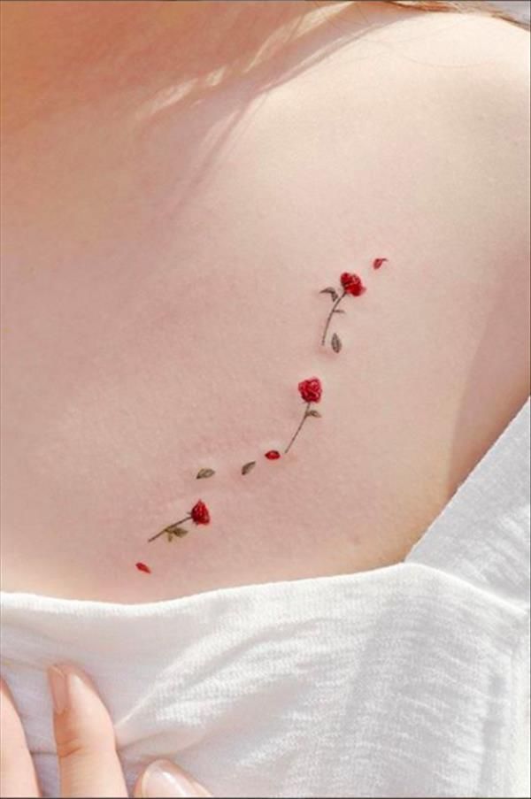 Minimalist red rose tattoo on skin, small floral design on upper chest.
