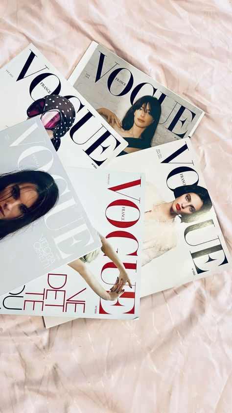 Collection of French Vogue magazines on a soft pink fabric background.