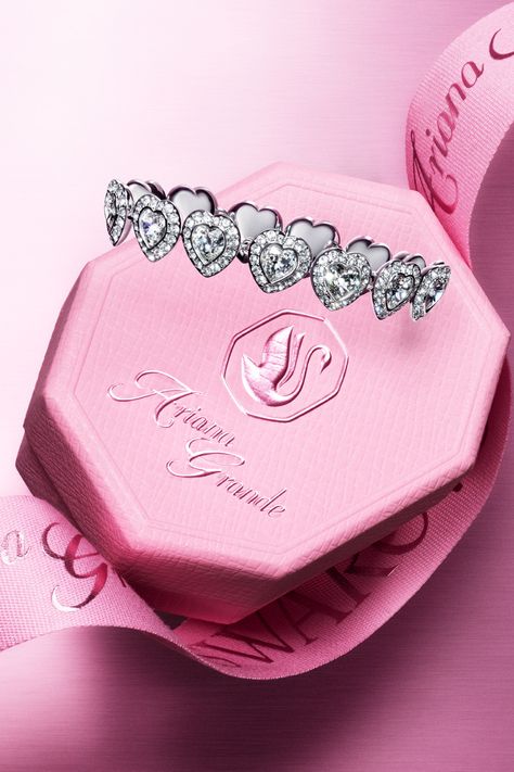 Heart-shaped diamond bracelet on a pink Ariana Grande branded box, symbolizing elegance and luxury.