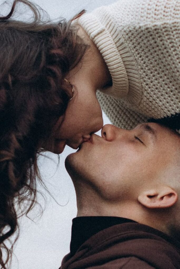Couple kissing tenderly outdoors, expressing love and connection. Cozy atmosphere with sweaters.