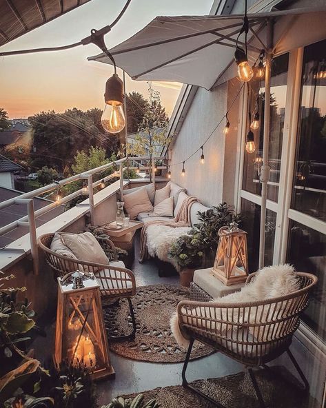 Cozy balcony with wicker chairs, string lights, and sunset view creating a warm, inviting outdoor seating space.