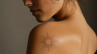 Close-up of minimalist sun tattoo on woman's shoulder and upper back, body art and skin detail