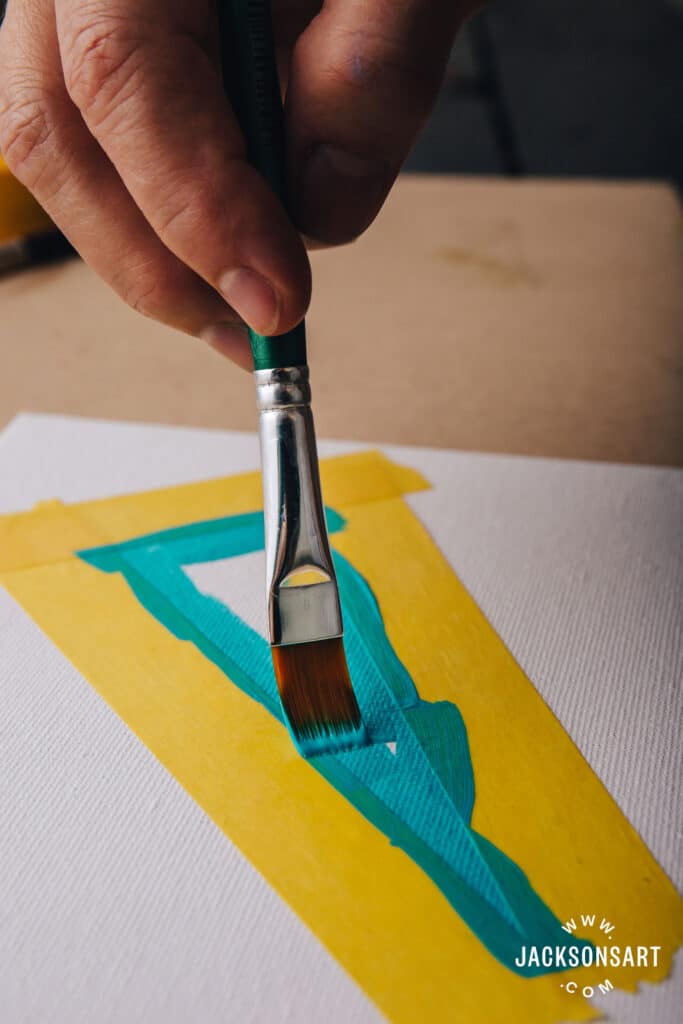 Hand painting canvas with green brushstroke and yellow tape border.
