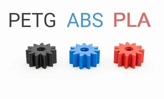 Black, blue, and red 3D printed gears made of PETG, ABS, and PLA materials on a white background.