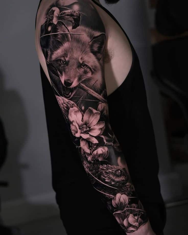 Intricate sleeve tattoo featuring a realistic fox and detailed flowers, showcasing vibrant black and white artistry.