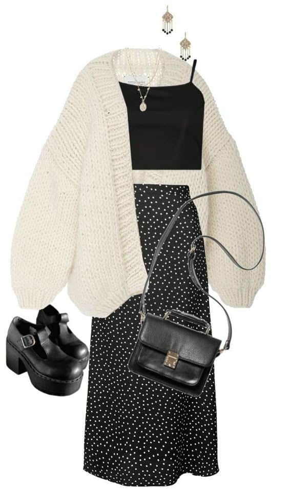 Chic outfit with a cream cardigan, black crop top, polka dot skirt, black shoes, and handbag, styled with jewelry.