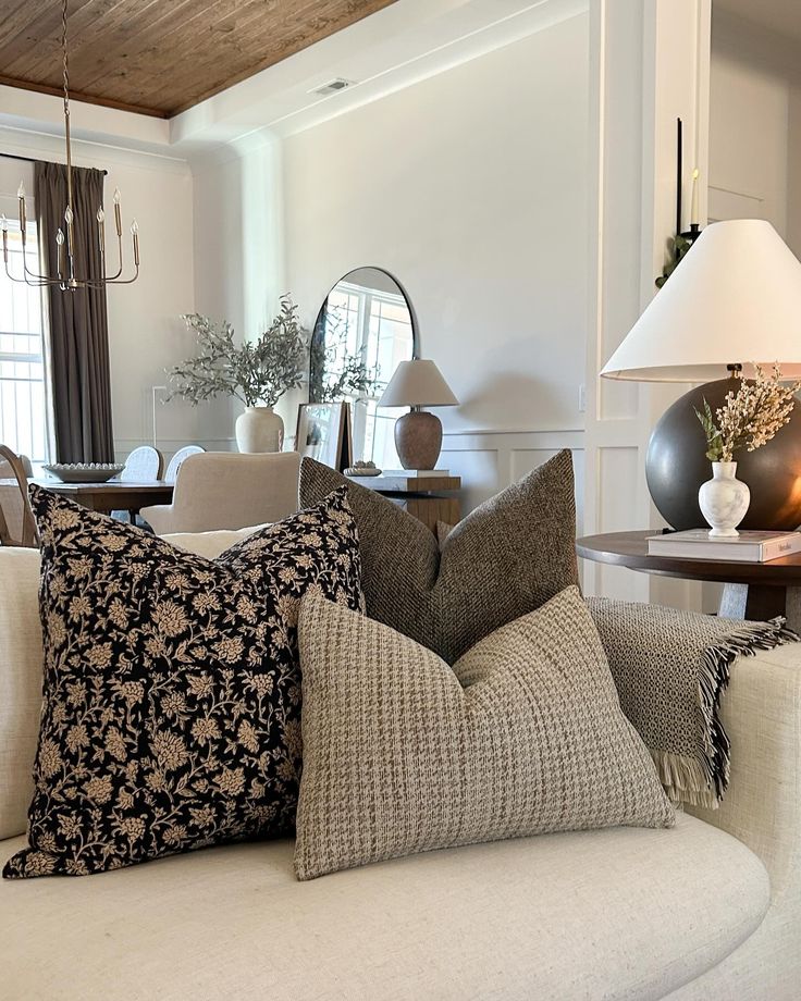Elegant living room with patterned throw pillows, cozy beige sofa, and a reflective mirror accent in warm lighting.