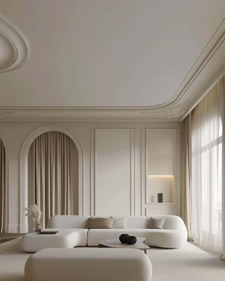 Minimalist beige living room with curved couches, soft lighting, and elegant drapes. Modern and serene interior design.