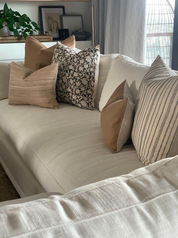 Stylish beige sofa with assorted throw pillows in a cozy living room setting.