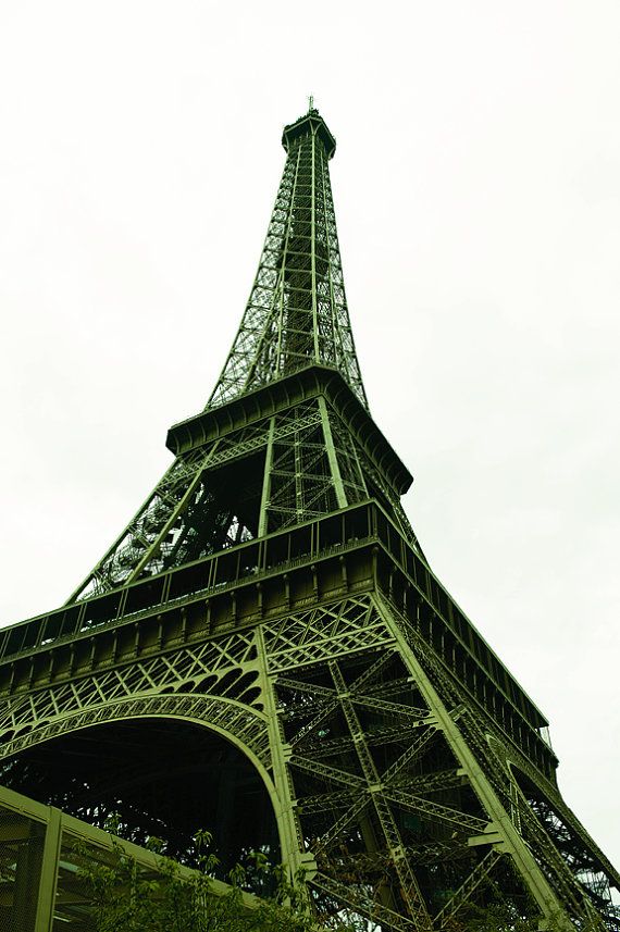 Looking up at the Eiffel Tower in Paris against a cloudy sky, showcasing its intricate iron lattice design.