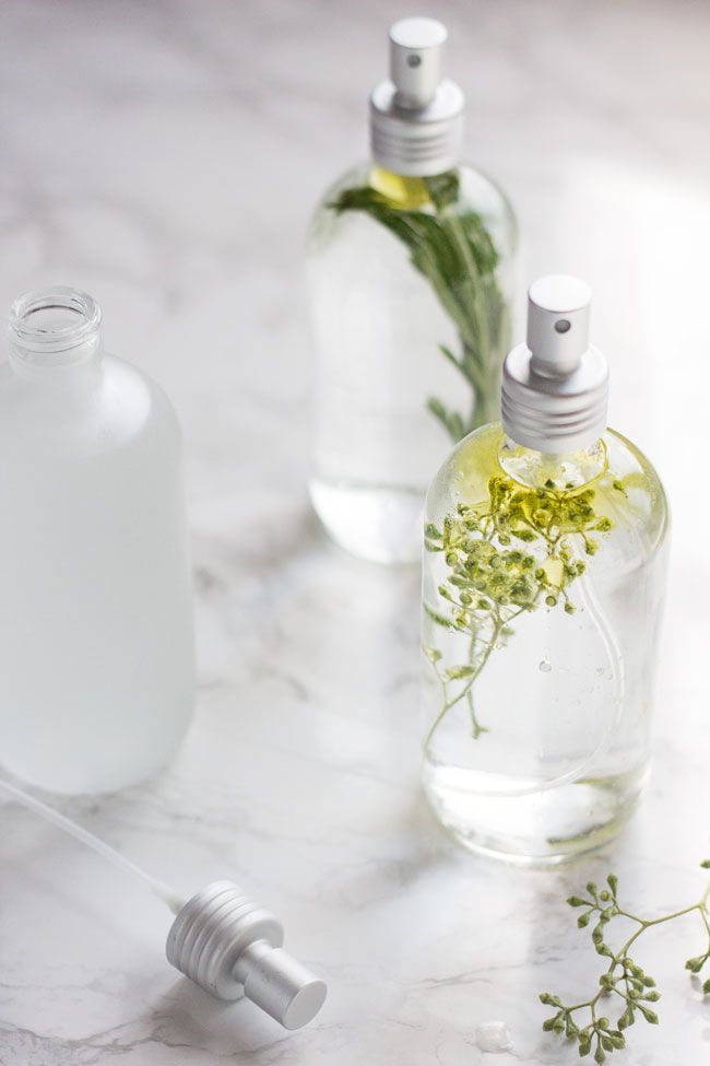 Herbal-infused glass spray bottles on a marble surface, perfect for natural skincare or homemade cleaning products.