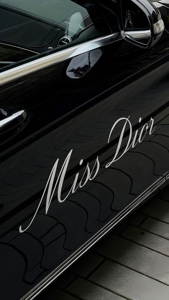 Close-up of a car door with Miss Dior elegantly written in cursive, reflecting luxury and style.