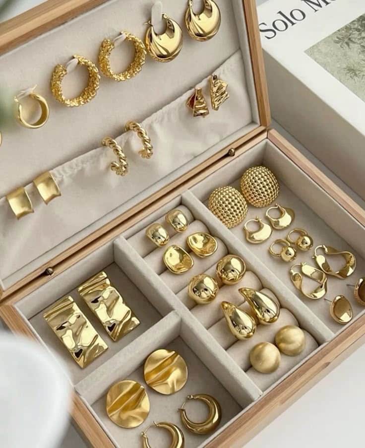 Elegant gold earrings displayed in an organized jewelry box, showcasing various stylish designs.